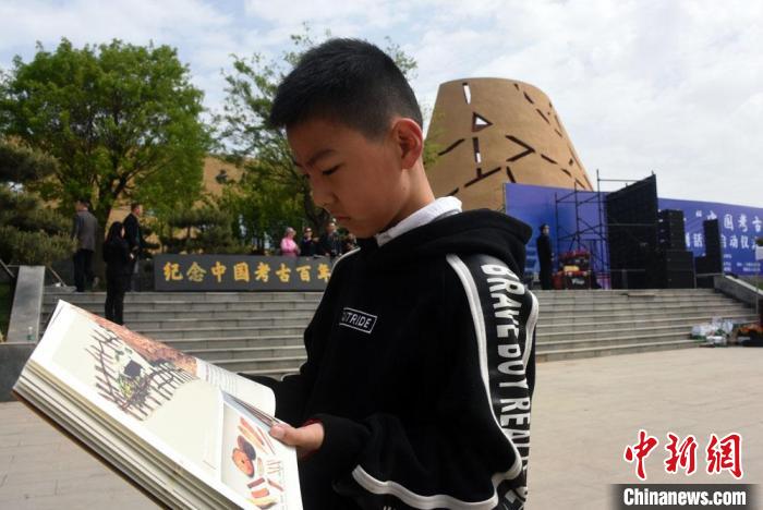 纪念“中国考古百年”系列活动在仰韶遗址举行启动仪式，一位少年在会场认真阅读《仰韶文化》图书。　孙自法 摄
